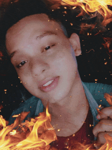 a young man in a blue shirt is surrounded by fire