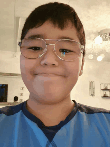 a boy wearing glasses and a blue shirt is smiling