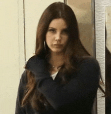 a woman with long brown hair is standing in front of a wall