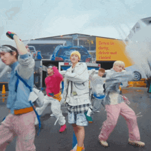 a group of young people are dancing in front of a sign that says drive in dirty drive out clean