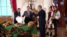 a group of people are standing in front of a table with flowers and a sign that says white house gov