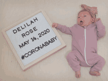 a newborn baby laying next to a sign that says delilah rose may 14 2020 #coronababy