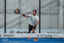 a man playing a game of paddle tennis in front of a skoda sign