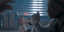 a man is eating an ice cream sundae with a cherry on top in a diner .