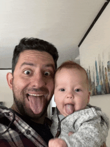 a man holding a baby sticking out his tongue