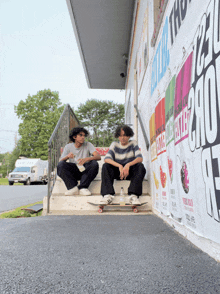 two young men sit on a set of stairs in front of a sign that says ' the ' on it