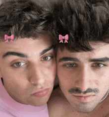 two men with pink bows on their hair are posing for a picture