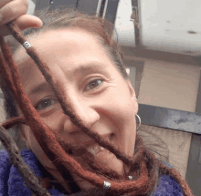 a woman with dreadlocks is smiling and holding her hair