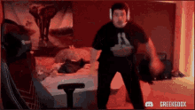 a man wearing headphones is dancing in front of a bed in a room .