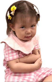 a little girl with her arms crossed is wearing a pink and white dress