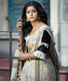 a woman with a red dot on her forehead is wearing a white saree and black blouse