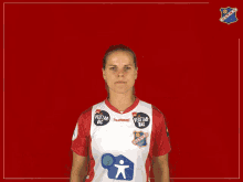 a woman wearing a red and white hummel shirt is making a face