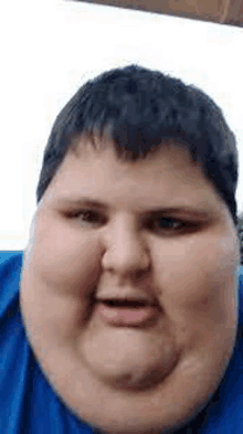 a close up of a fat boy 's face with a blue shirt on .