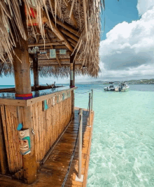 a tiki bar on a dock overlooking the ocean with boats in the distance .