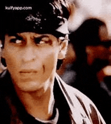 a close up of a man wearing a bandana on his head and looking at the camera .