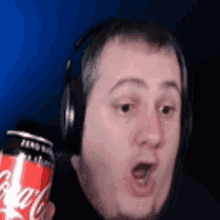 a man wearing headphones is holding a can of coca-cola .