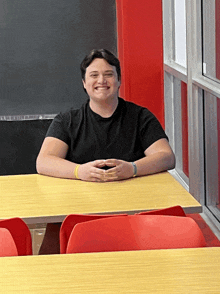 a man sits at a table with his hands folded