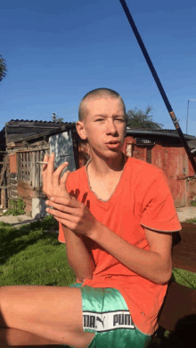 a young man wearing a red shirt and green shorts with puma written on them