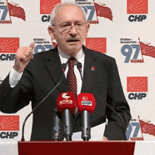 a man in a suit and tie is giving a speech at a podium in front of a wall that says chp 97