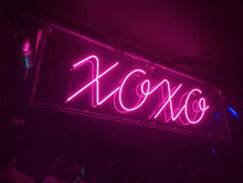 a neon sign that says " xoxo " in a dark room