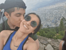 a man kisses a woman on the cheek while wearing sunglasses and a necklace that says ' amanda '