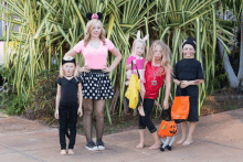 a woman in a minnie mouse costume stands next to a group of children