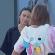 a woman wearing a unicorn hoodie is looking at another woman