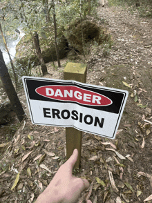 a person points to a danger erosion sign