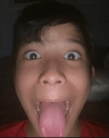 a young boy with his tongue out making a face