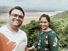 a man and a woman are posing for a picture and the man is wearing glasses