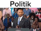 a man in a suit and tie stands at a podium in front of a crowd with the word politik above him