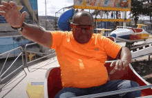 a man in an orange shirt is riding a roller coaster in front of a sign that says " play "