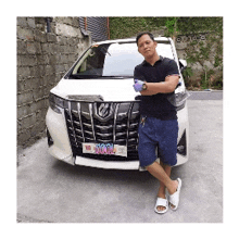 a man is standing in front of a white car with a license plate that says t100l