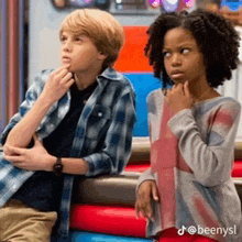 a boy and a girl are sitting next to each other on a couch looking at something .