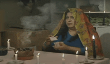 a woman is sitting at a table with candles and smoke coming out of her head