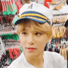 a young man wearing a captain 's hat and a white shirt is standing in a store .