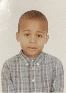 a young boy wearing a blue plaid shirt looks at the camera