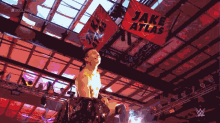 a man in a wrestling ring with a banner that says jake atlas