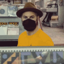 a man wearing a hat and a face mask is standing in front of a shelf with a book displayed on it