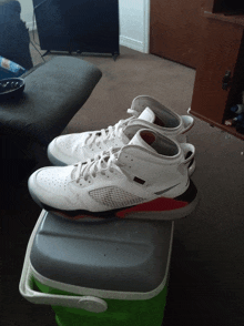 a pair of white and red shoes sit on top of a green cooler