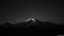 a black and white photo of a mountain with a dark sky in the background