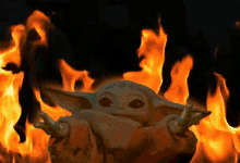 a baby yoda is surrounded by flames in the dark