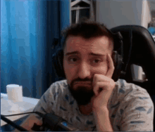 a man with a beard is wearing headphones and making a sad face