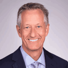 a man wearing a suit and tie is smiling for the camera