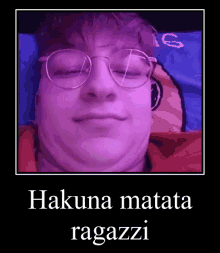 a man wearing glasses is laying on a bed with the words hakuna matata ragazzi on the bottom .