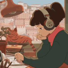 a girl wearing headphones is sitting at a desk writing in a notebook while a cat sits on a window sill .