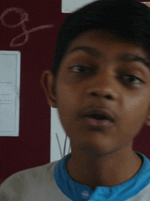 a close up of a boy 's face with the letter g written on a wall behind him