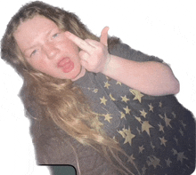 a girl with long hair is giving the middle finger and wearing a shirt with stars on it