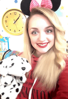 a woman wearing minnie mouse ears holds a stuffed animal