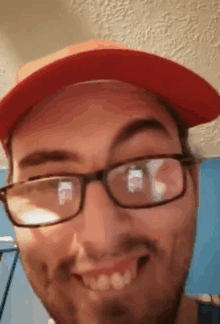 a man wearing glasses and a red hat is making a funny face .